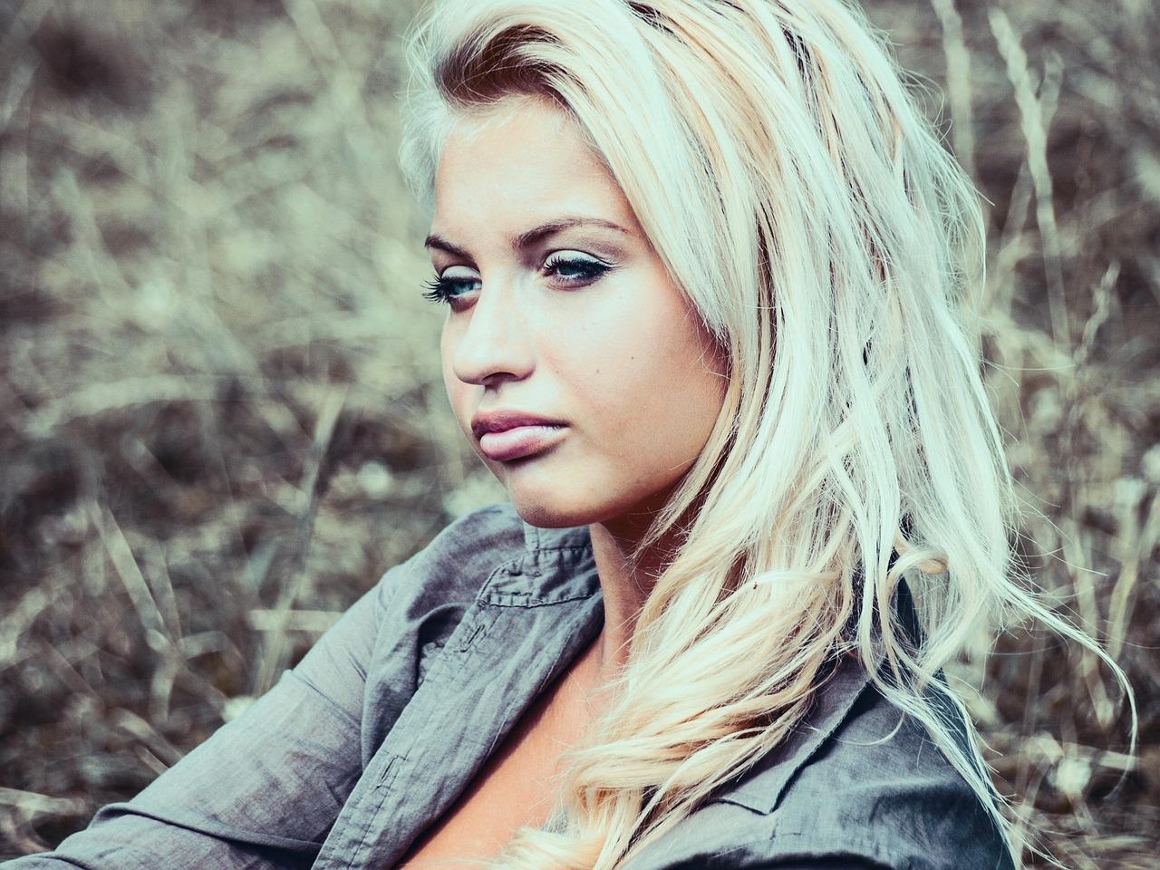 Blonde vrouw toont gezonde geblondeerde haren met glans en blijkt effect na juiste verzorging en kappersbehandeling